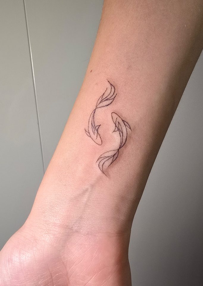 Tattoo von stilisierten Fischen auf dem Unterarm.