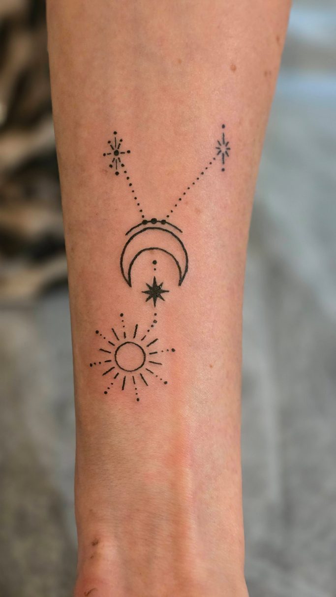 Tattoo am Unterarm mit Sonnen- und Mondsymbolen sowie dekorativen Linien.